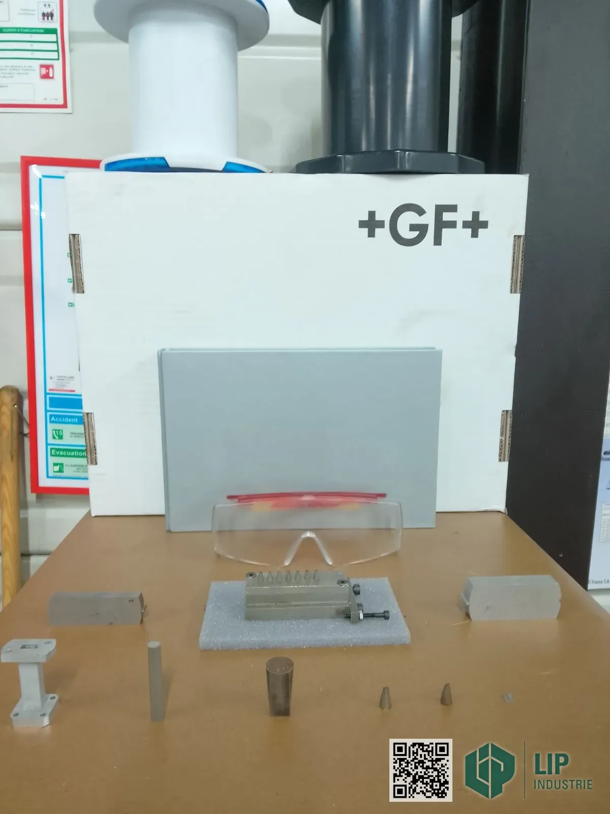Pièces de précision usinées en électroérosion fil (profils, cônes et blocs métalliques) devant une machine +GF+